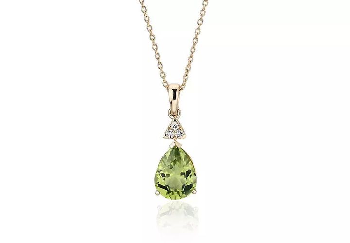 A teardrop-shaped peridot gemstone pendant topped with a trio of diamonds set in yellow gold and yellow gold chain.